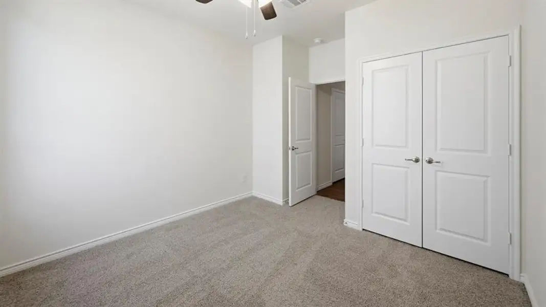 Room featuring light grey carpeting, white baseboards, and a white ceiling with a ceiling fan Room featuring light grey carpeting, white baseboards, and a white ceiling with a ceiling fan