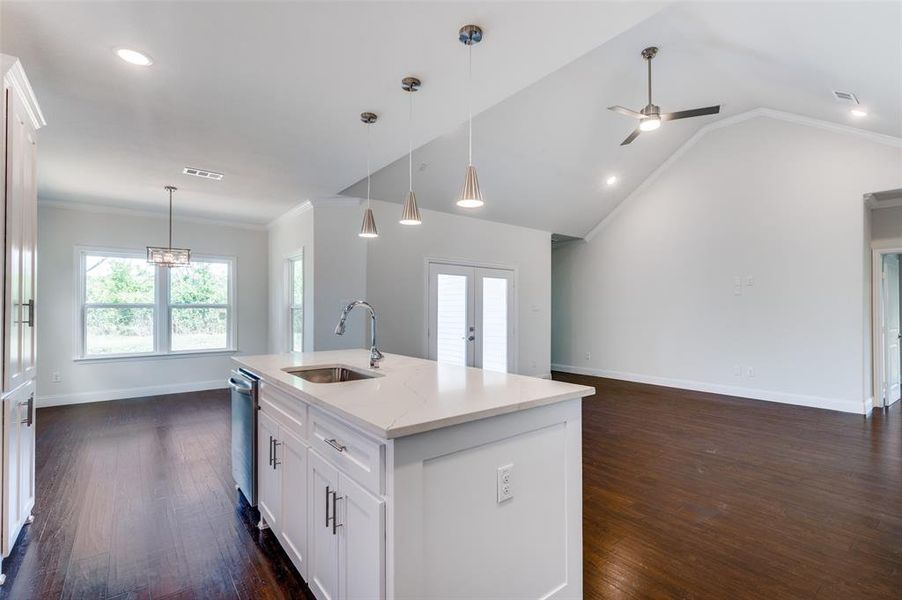 Kitchen with dark hardwood / wood-style floors, ornamental molding, and an island with sink