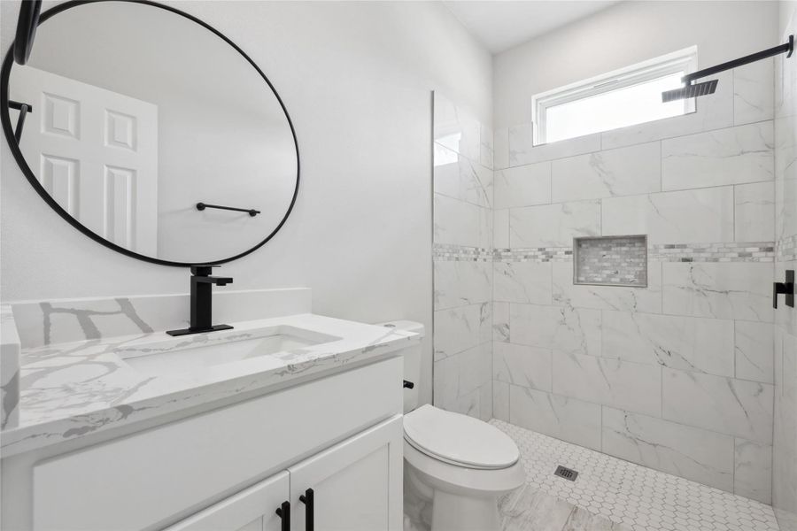 Full bath featuring vanity, toilet, and a tile shower Full bath featuring vanity, toilet, and a tile shower