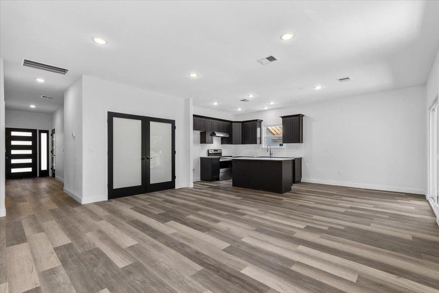 Plank flooring and recessed lighting flow through this open space into the kitchen. Plank flooring and recessed lighting flow through this open space into the kitchen.