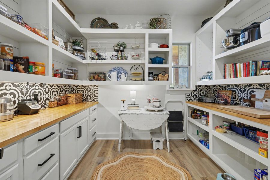 View of pantry with open shelving cabinets drawers and butcher block prep area