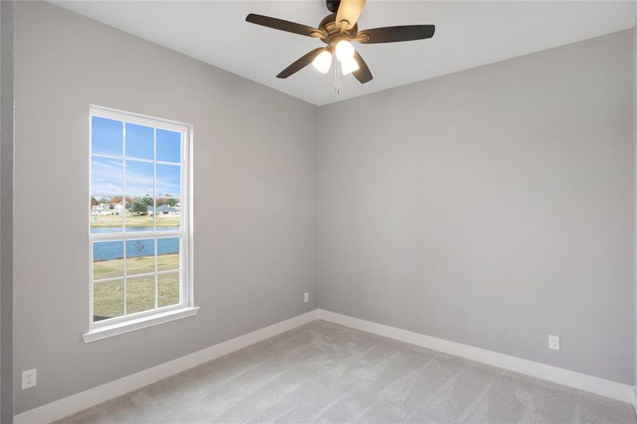Spare room with light colored carpet, a water view, and ceiling fan Spare room with light colored carpet, a water view, and ceiling fan