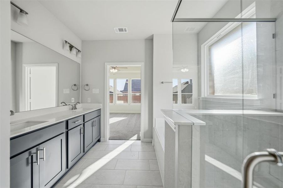 Full bath featuring double vanity, a shower stall, light tile patterned floors, a ceiling fan, and light colored carpet Full bath featuring double vanity, a shower stall, light tile patterned floors, a ceiling fan, and light colored carpet