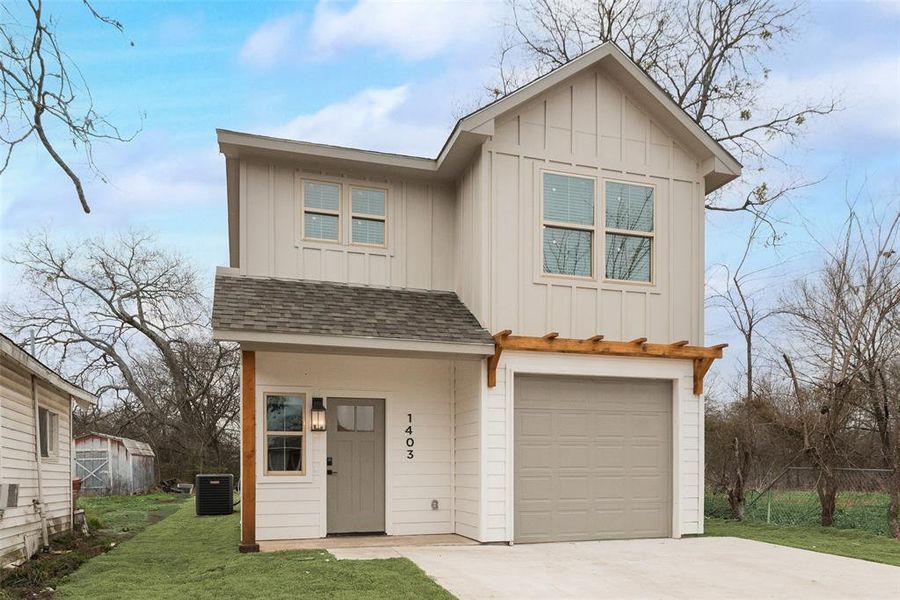 View of front of house featuring a garage, central air condition unit, and a front lawn