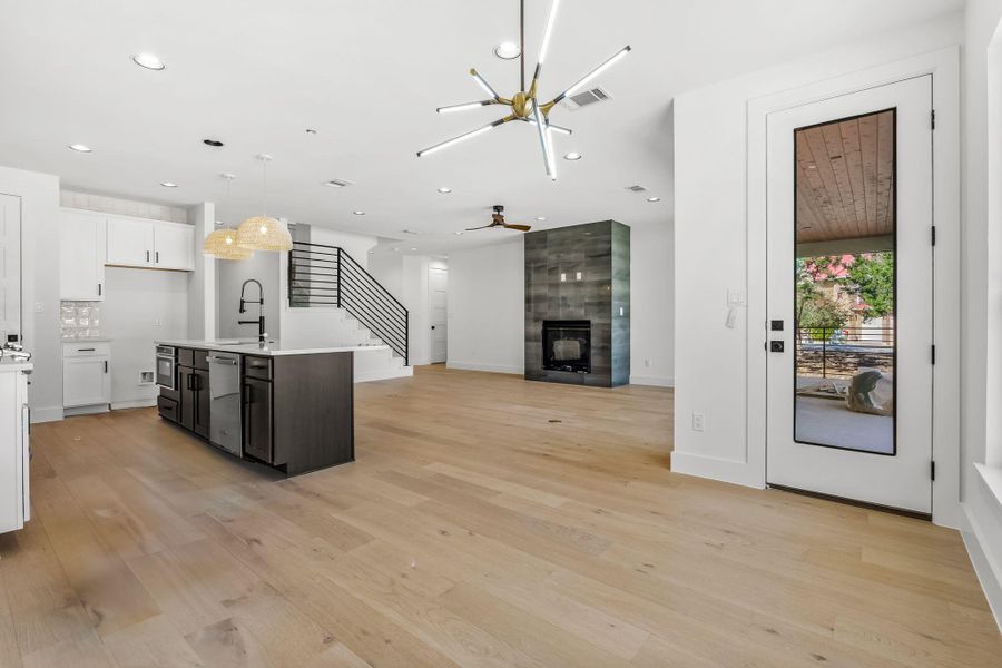 Kitchen featuring light wood finished floors, visible vents, a fireplace, stainless steel dishwasher, and a sink