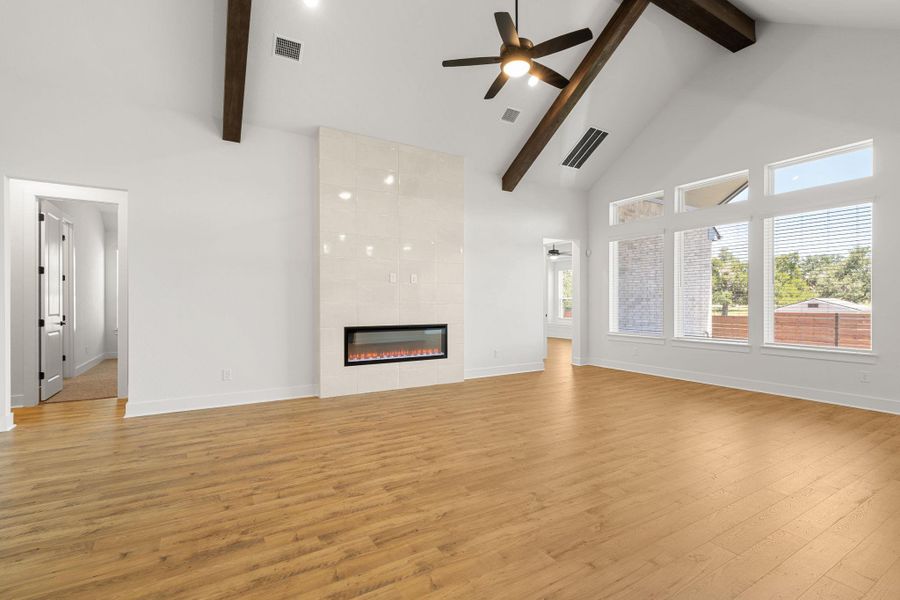 Vast living space with soaring vaulted ceilings, hardwood floors, and an elegant fireplace creates an inviting atmosphere.