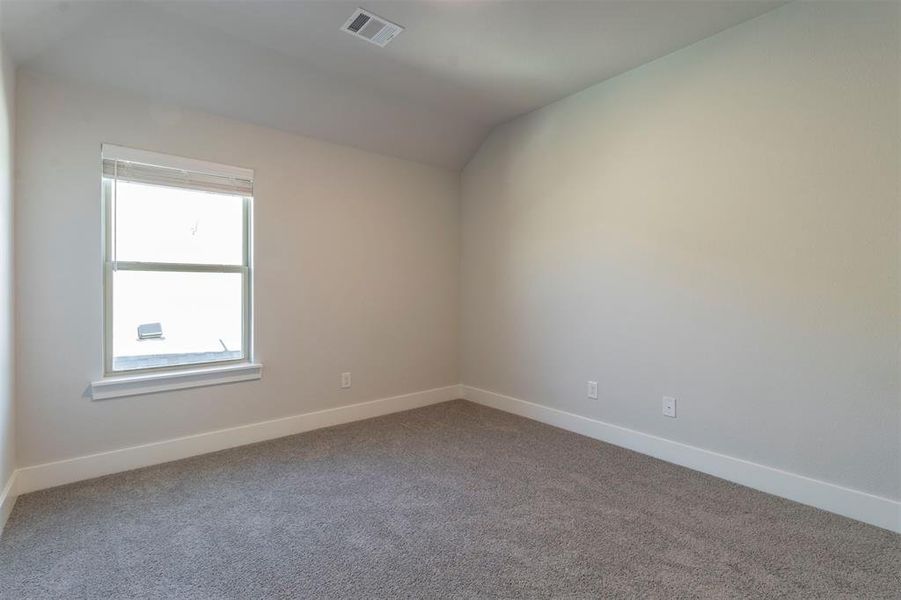 Carpeted spare room with vaulted ceiling and baseboards