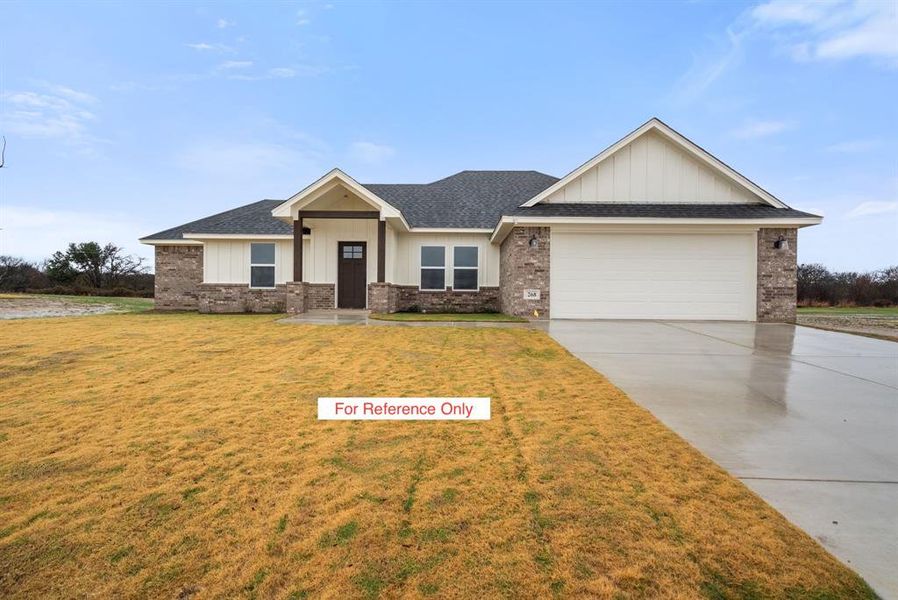 View of front of home with a front lawn, brick siding, driveway, and board and batten siding