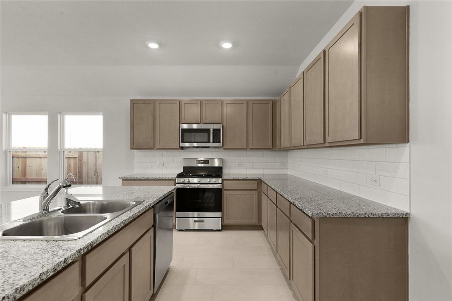 Kitchen with stainless steel appliances, backsplash, light stone counters, recessed lighting, and wood finish cabinets
