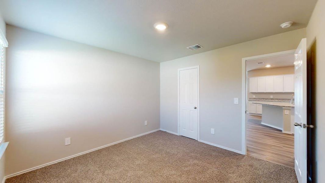 A well-lit interior room with a door leading to a modern kitchen featuring an island.