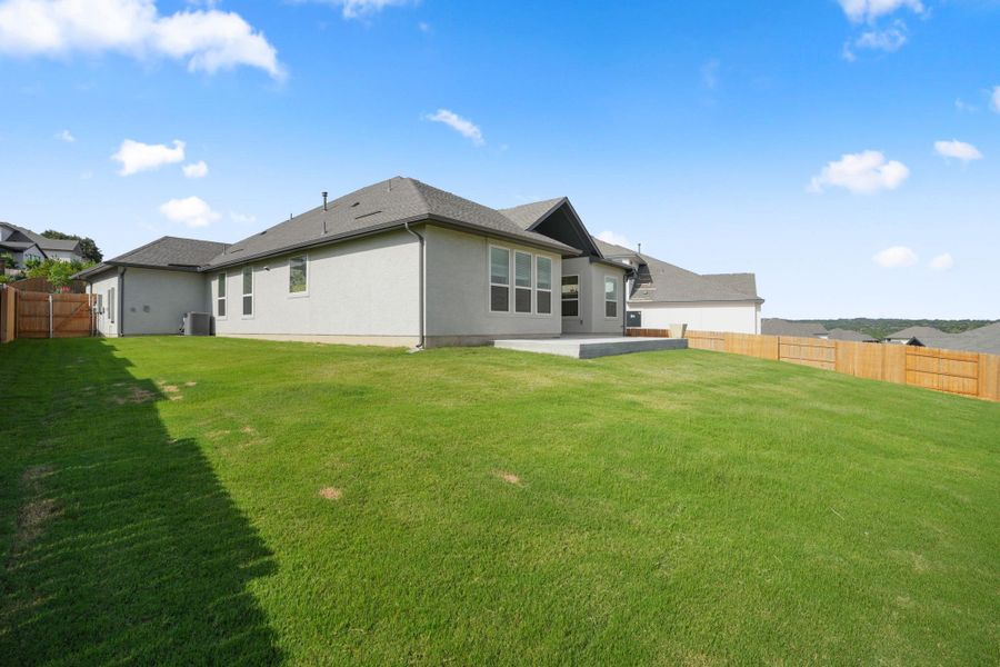 A generous lawn and sturdy privacy fencing define the backyard space.