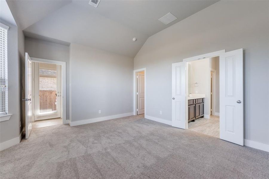 Unfurnished bedroom featuring vaulted ceiling, light colored carpet, and ensuite bath