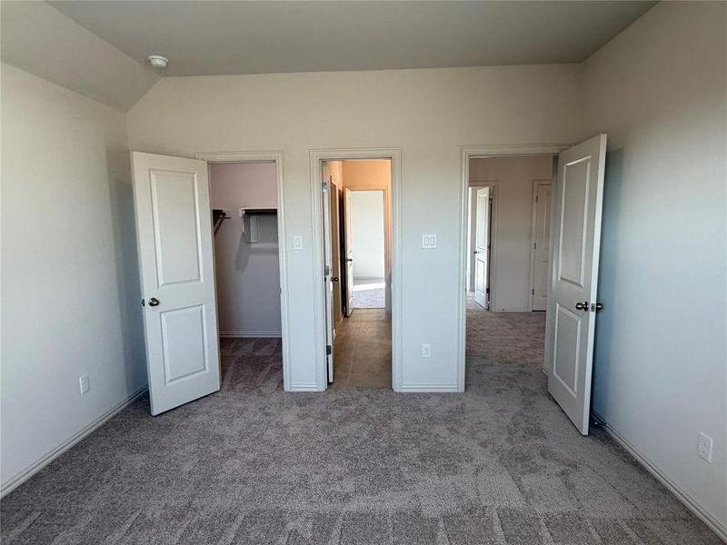 Carpeted room featuring multiple doorways and a closet with built-in shelving Carpeted room featuring multiple doorways and a closet with built-in shelving
