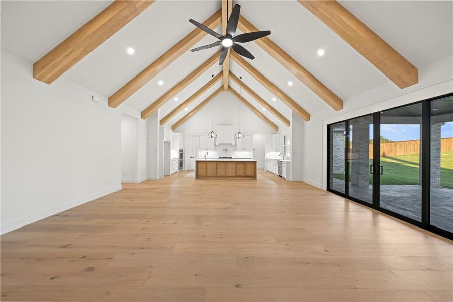 Unfurnished living room featuring light wood finished floors, beamed ceiling, high vaulted ceiling, a ceiling fan, and recessed lighting