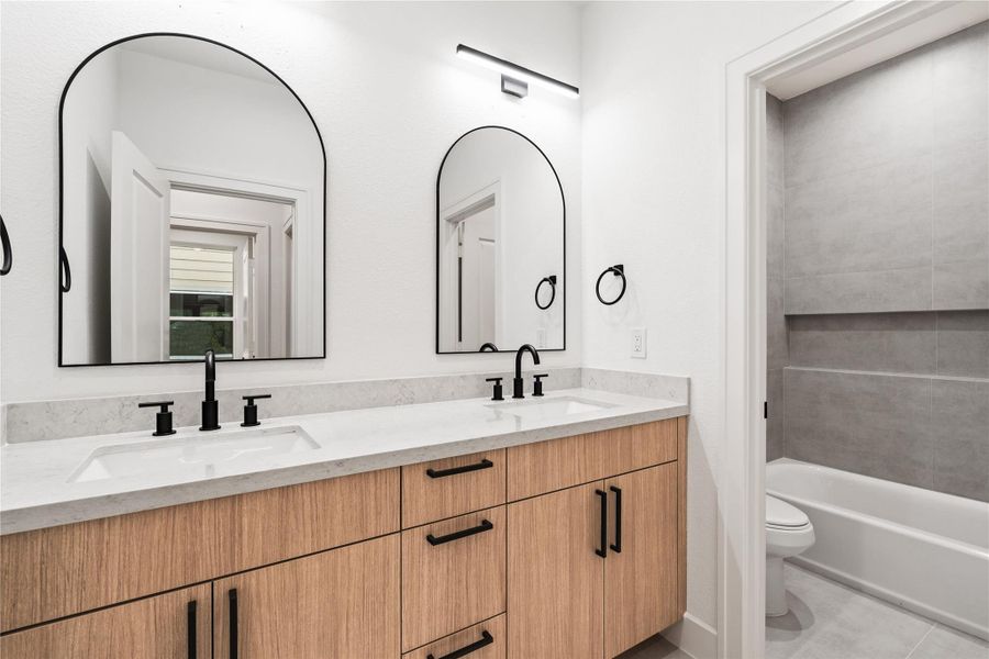 A full bath that carries thehome’s modern DNA — oakcolored cabinetry, quartzcounters, and streamlinedfixtures.