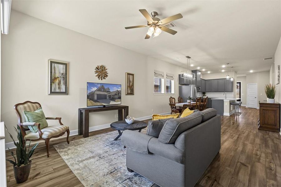 Living room with recessed lighting, baseboards, dark wood-style flooring, and ceiling fan with notable chandelier