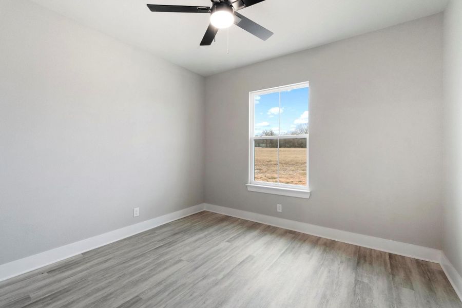 Empty room with light wood-style flooring and ceiling fan