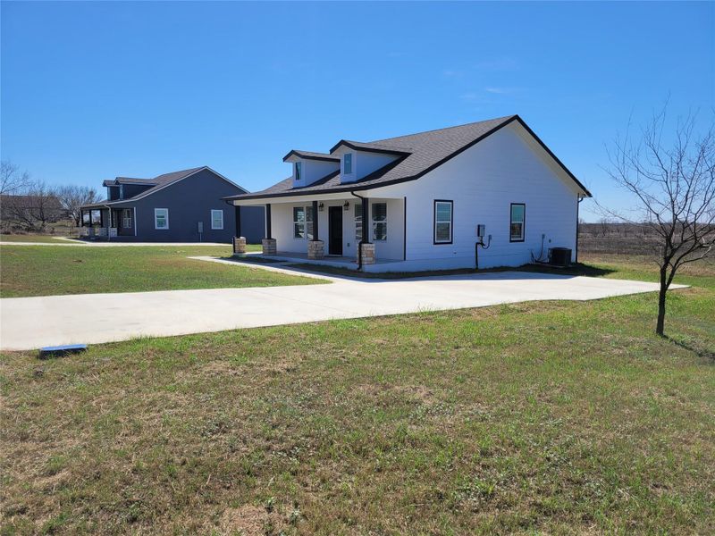 A newly built residence with a clean, modern aesthetic, features a wide concrete driveway and inviting covered porch. A newly built residence with a clean, modern aesthetic, features a wide concrete driveway and inviting covered porch.
