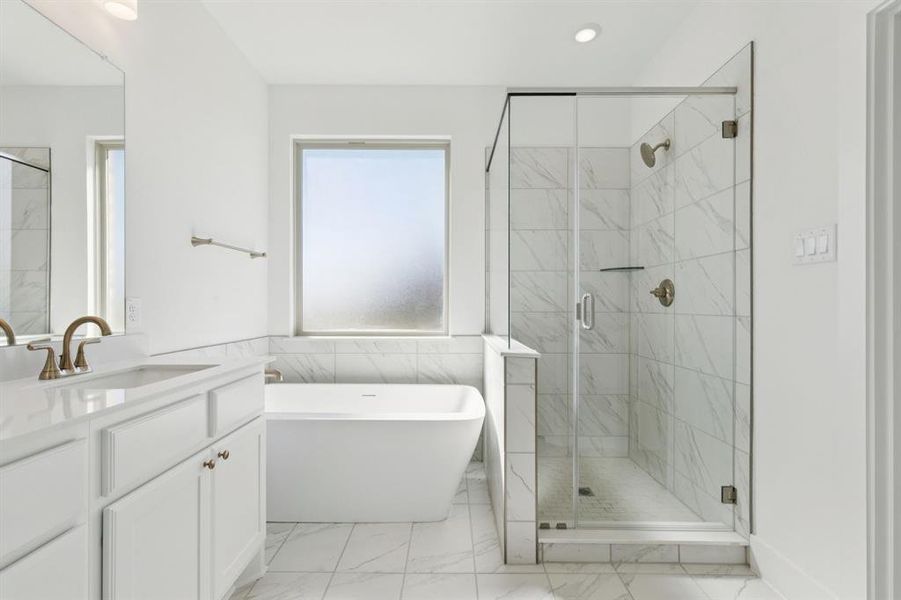 Full bath featuring vanity, a freestanding bath, light marble finish flooring, a marble finish shower, and recessed lighting