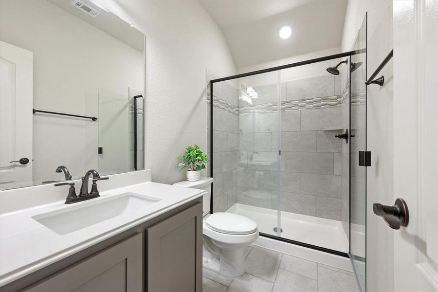 Additional full bathroom upstairs features a spacious walk in tile surround shower, tile flooring, large vanity with undermount sink, elongated toilet and bronze fixtures and hardware.