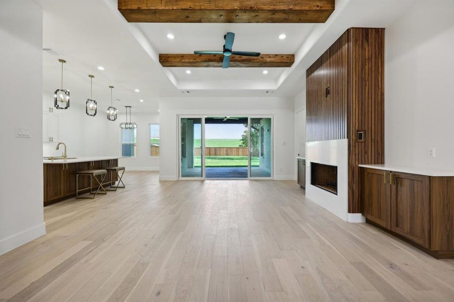 Unfurnished living room featuring light hardwood / wood-style flooring, beam ceiling, and ceiling fan