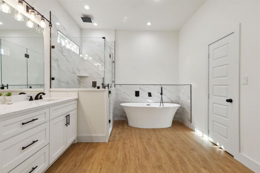 Bathroom featuring vanity, tile walls, wood-type flooring, and shower with separate bathtub