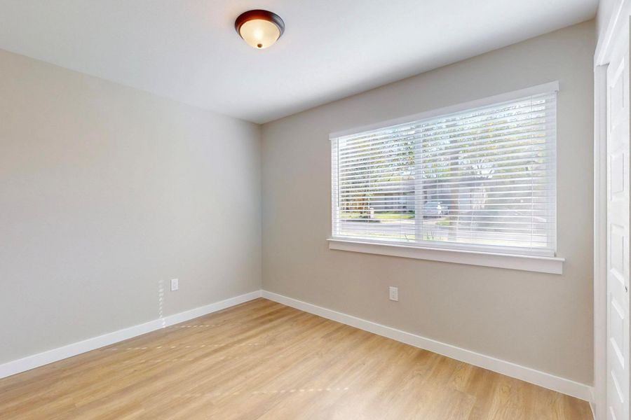 Primary bedroom has nice size closet, ceiling fan, large low e window, blinds and has an on suite full bathroom. Unfurnished room featuring light wood-style flooring, plenty of natural light, and baseboards