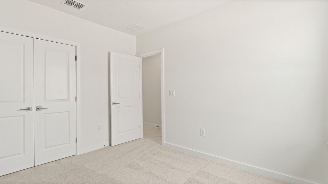 Bedroom with plush carpet, double-door closet, and neutral wall color in the Castaway model by DRB Homes in Hamilton Bluff