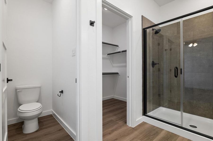 Bathroom with hardwood / wood-style floors, toilet, and an enclosed shower