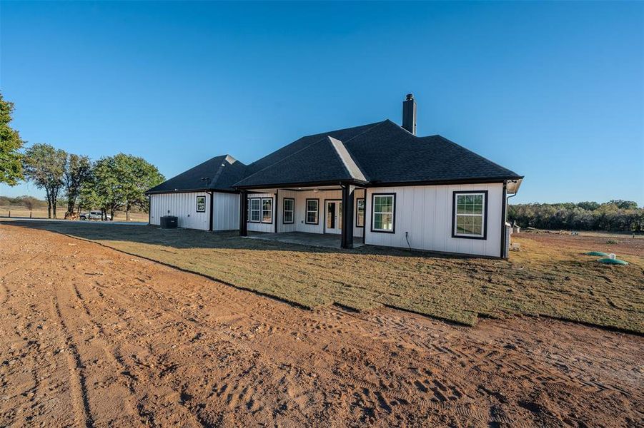 Back of property featuring a patio, a chimney, and a shingled roof Back of property featuring a patio, a chimney, and a shingled roof