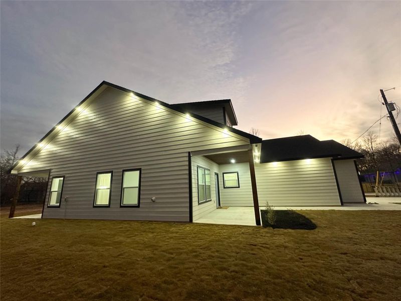 Back of house at dusk with a patio and a yard
