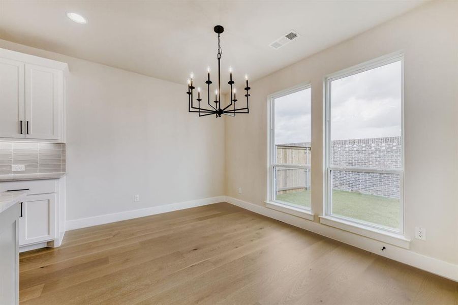 Open-concept interior featuring wood-finish flooring, a contemporary black chandelier, and recessed lighting