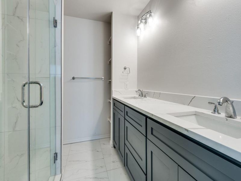 Bathroom featuring walk in shower, double vanity, and tile patterned flooring