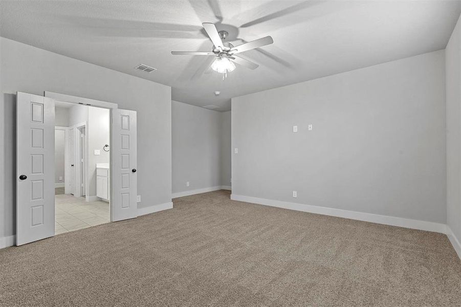 Unfurnished bedroom with light carpet, ceiling fan, and ensuite bath