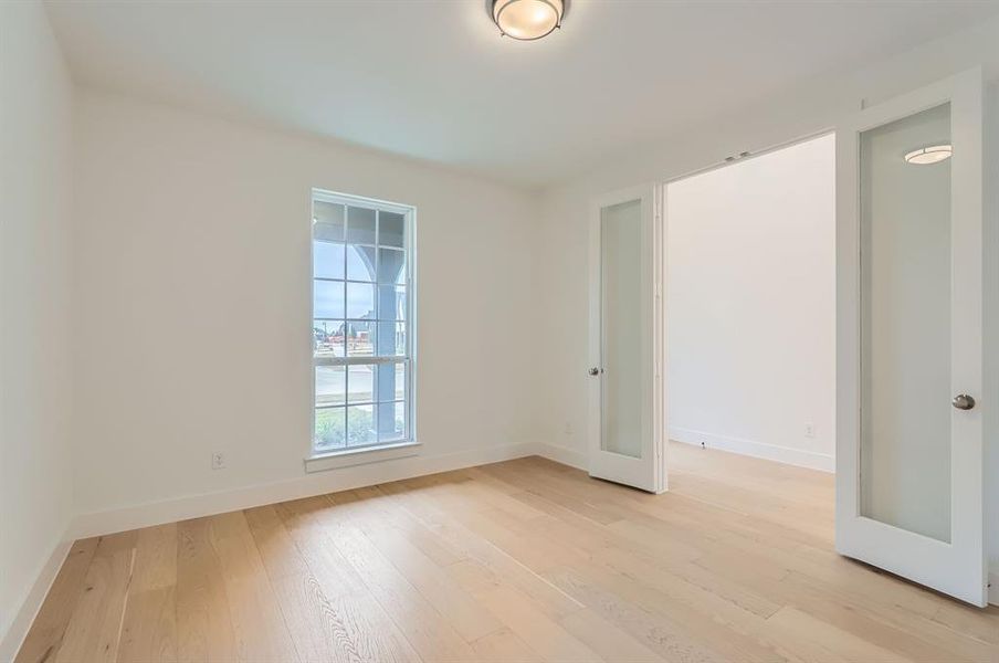 Empty room featuring french doors and light wood-type flooring