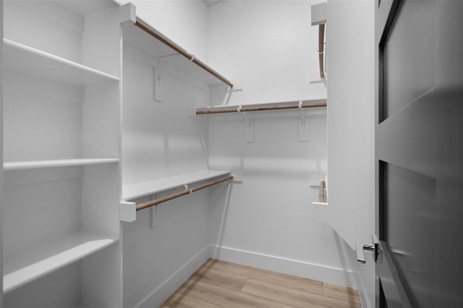 Well-appointed closet featuring white shelving, hanging rods, and light wood-style flooring Well-appointed closet featuring white shelving, hanging rods, and light wood-style flooring