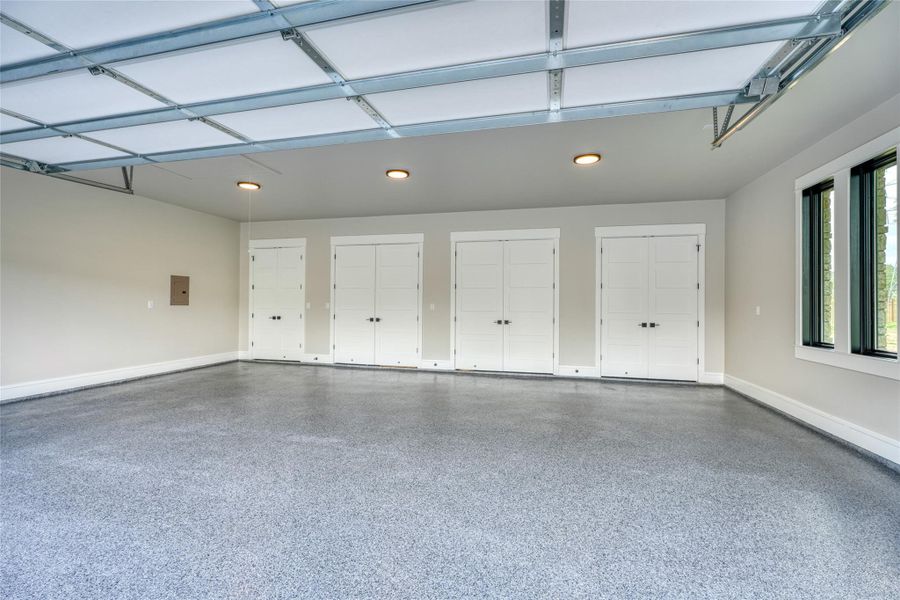 Garage with baseboards, electric panel, and recessed lighting