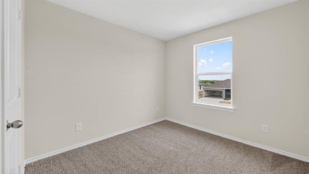 Room featuring a neutral color palette, light gray walls, textured carpet, white trim, and a window providing natural illumination