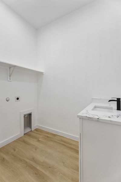 Functional utility space features warm wood floors and a contemporary vanity with stone counters.