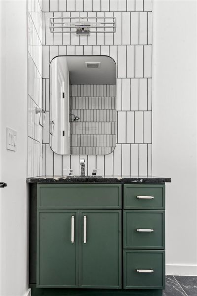 Bathroom with vanity, decorative backsplash, and dark marble finish flooring