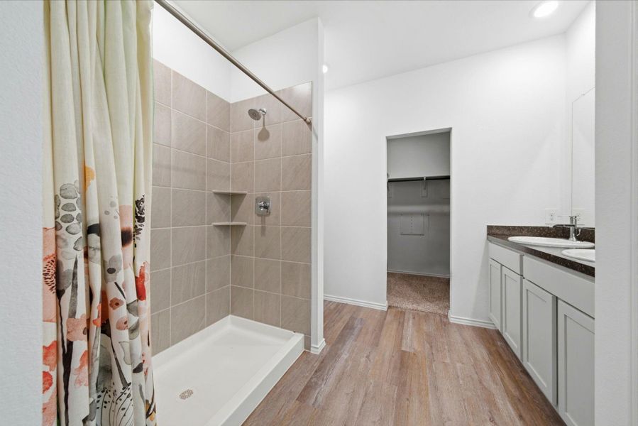 Open, airy bathroom with a large shower and warm vinyl plank floors for a calm, upscale feel.