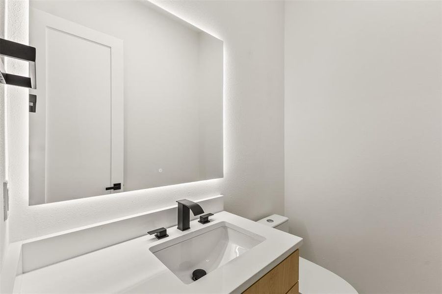 Contemporary vanity featuring a rectangular undermount sink, matte black faucet, and a light wood-finish cabinet