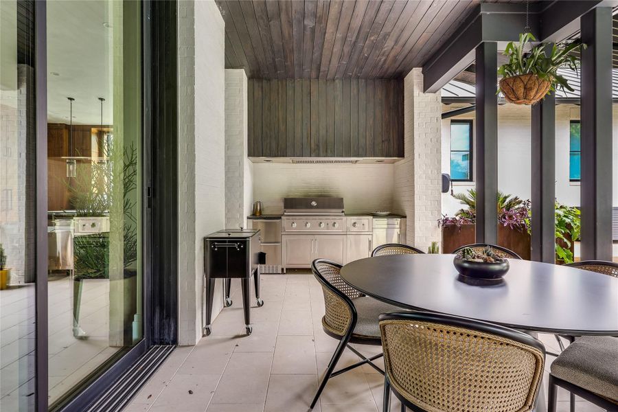 The outdoor kitchen features built-in refrigeration, a gas grill, and plenty of sitting space.
