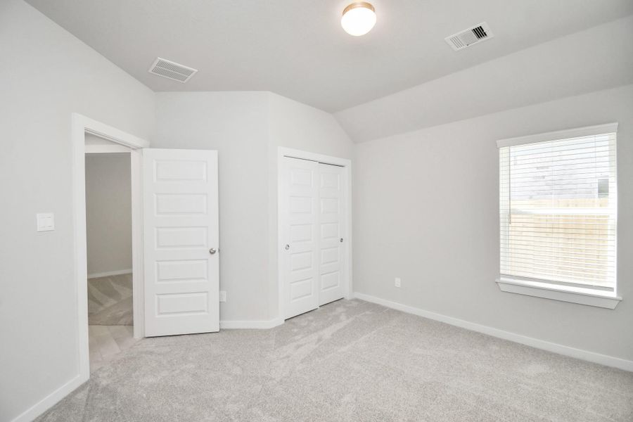 Secondary bedroom features plush carpeting, large windows that let in plenty of natural light, bright paint, and spacious closets. Sample photo of completed home with similar floor plan. Actual colors and selections may vary.