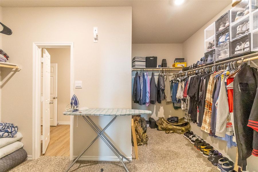 An organized walk-in closet featuring extensive hanging space and convenient upper shelving.