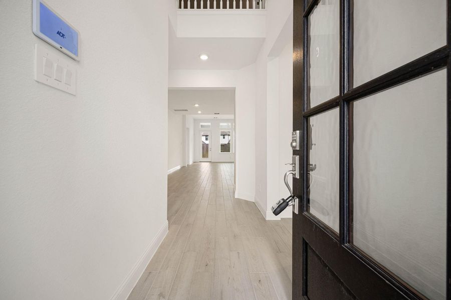 Step into a bright and inviting entryway with sleek wood flooring and high ceilings, leading to spacious interiors filled with natural light.