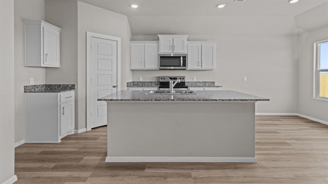 Kitchen featuring stainless steel microwave, a sink, dark stone countertops, white cabinets, and recessed lighting Kitchen featuring stainless steel microwave, a sink, dark stone countertops, white cabinets, and recessed lighting