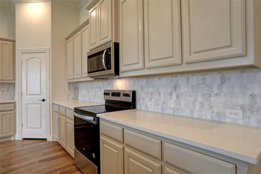 Kitchen with stainless steel appliances, light hardwood / wood-style flooring, and tasteful backsplash