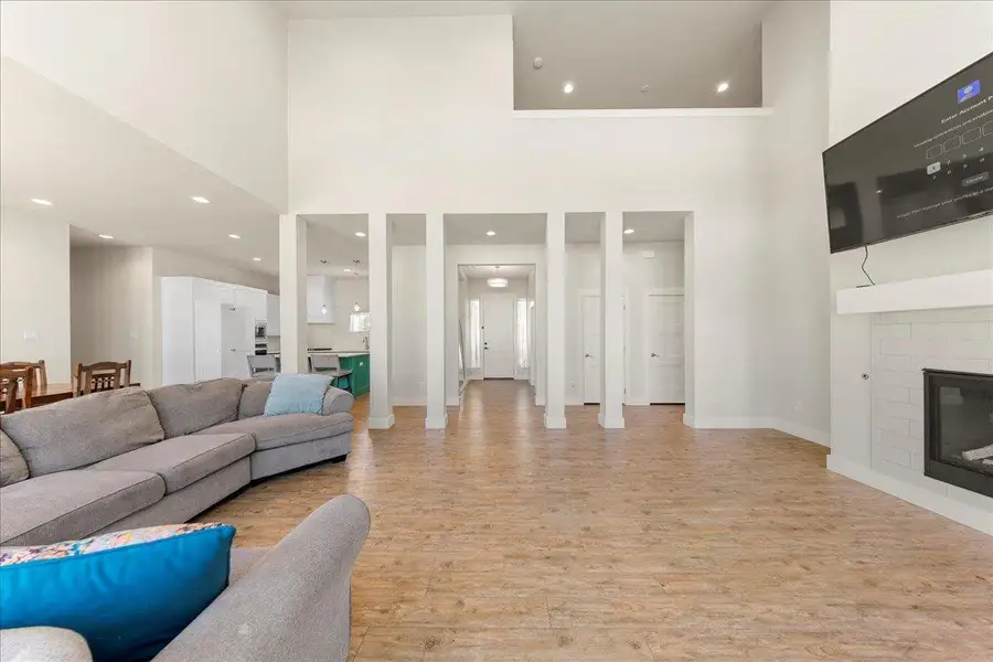 Living area with light wood-style flooring, recessed lighting, a towering ceiling, and a glass covered fireplace Living area with light wood-style flooring, recessed lighting, a towering ceiling, and a glass covered fireplace