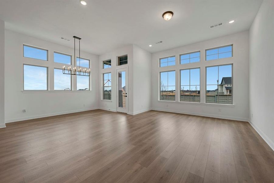 Unfurnished living room featuring a chandelier, dark wood-style flooring, and healthy amount of natural light